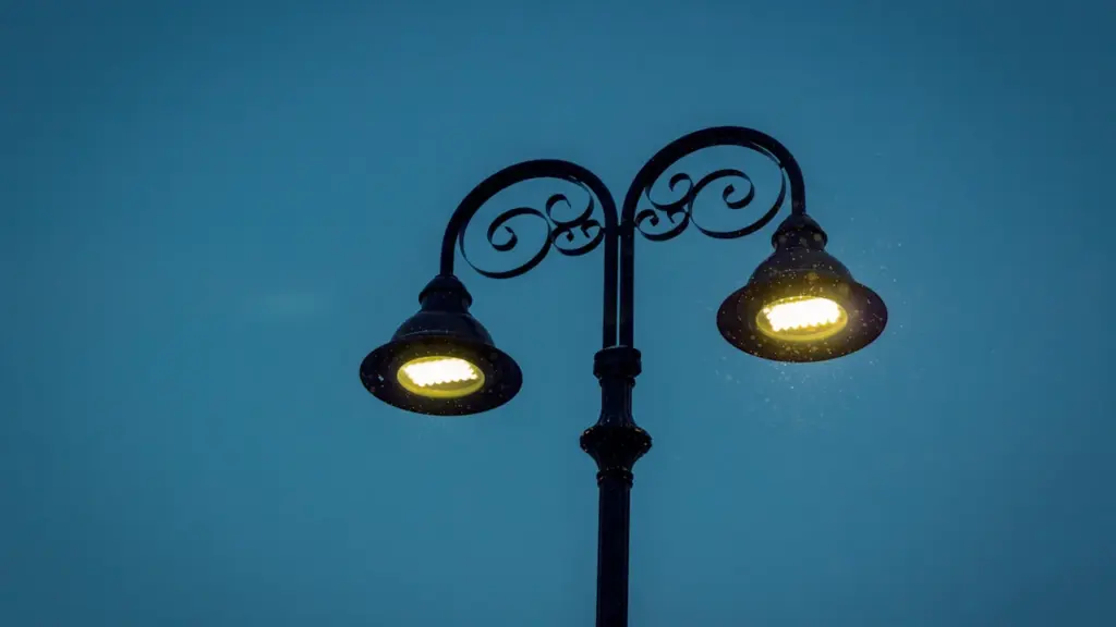 Nowoczesna lampa uliczna świecąca jasnym światłem na tle wieczornego nieba w mieście.