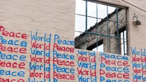 Napis World Peace namalowany farbą na zewnętrznej ścianie budynku z oknem