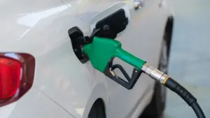 Pistolet dystrybutora paliwa wlewa benzynę do baku białego samochodu osobowego