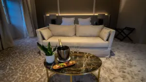Luksusowy pokój hotelowy z kanapą, stolikiem kawowym, szampanem i owocami w eleganckim wnętrzu.