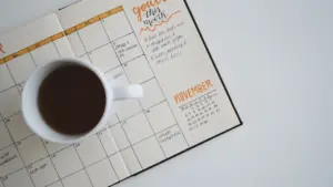 Otwarty planer miesięczny z filiżanką czarnej kawy na niedzielne planowanie.