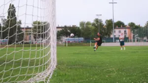 Piłkarz kopiący futbolówkę w stronę bramki na lokalnym boisku w Polsce