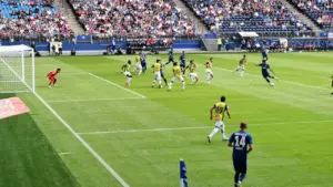 Piłkarze w trakcie dynamicznego meczu na stadionie podczas rozgrywek ligowych.