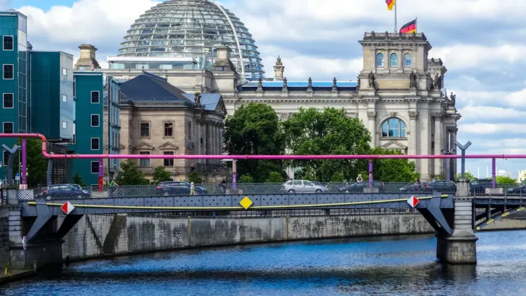 Budynek Reichstagu z przeszkloną kopułą nad rzeką Sprewą w Berlinie w słoneczny dzień.