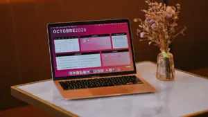 Otwarty laptop z widocznym kalendarzem na październik 2026 na marmurowym blacie.